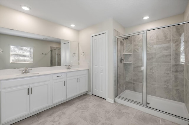 full bath with a stall shower, a sink, recessed lighting, and double vanity