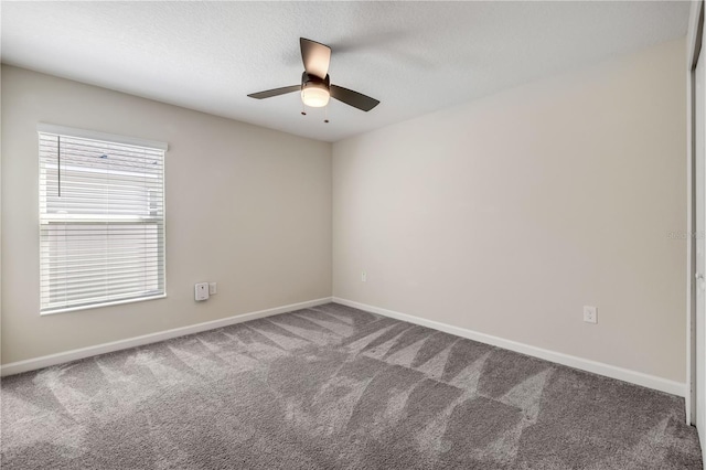 carpeted empty room featuring a textured ceiling, a ceiling fan, and baseboards