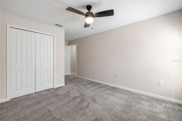 unfurnished bedroom with carpet, a closet, visible vents, a textured ceiling, and baseboards