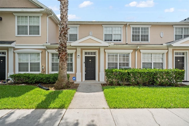 townhome / multi-family property with a front lawn and stucco siding