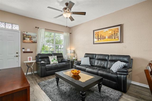 living area with baseboards, a ceiling fan, and wood finished floors