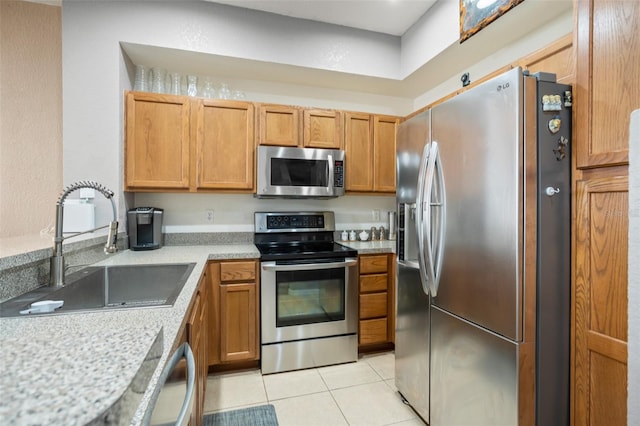 kitchen featuring light tile patterned floors, brown cabinetry, stainless steel appliances, light countertops, and a sink