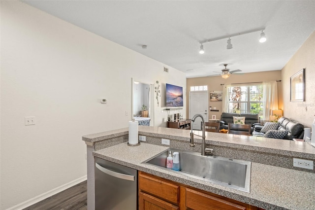 kitchen with brown cabinets, dark wood-type flooring, open floor plan, a sink, and dishwasher