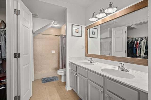 bathroom with double vanity, tile patterned flooring, toilet, and a sink