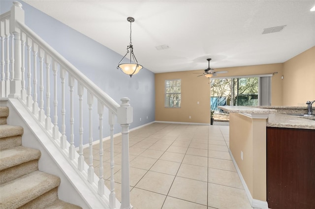 interior space featuring decorative light fixtures, light tile patterned floors, visible vents, ceiling fan, and baseboards