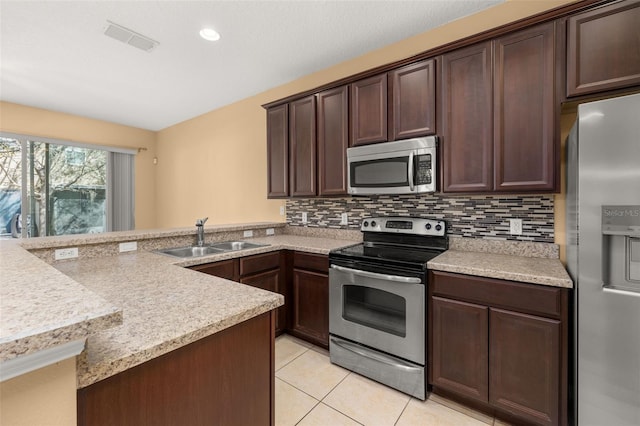 kitchen featuring dark brown cabinetry, visible vents, decorative backsplash, stainless steel appliances, and a sink