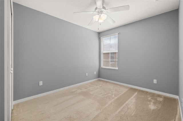 carpeted empty room featuring ceiling fan and baseboards