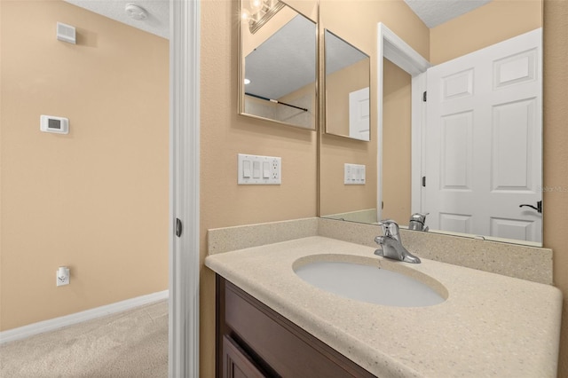 bathroom featuring a textured ceiling, vanity, and baseboards