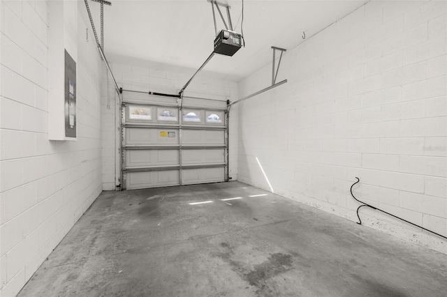 garage featuring concrete block wall, electric panel, and a garage door opener