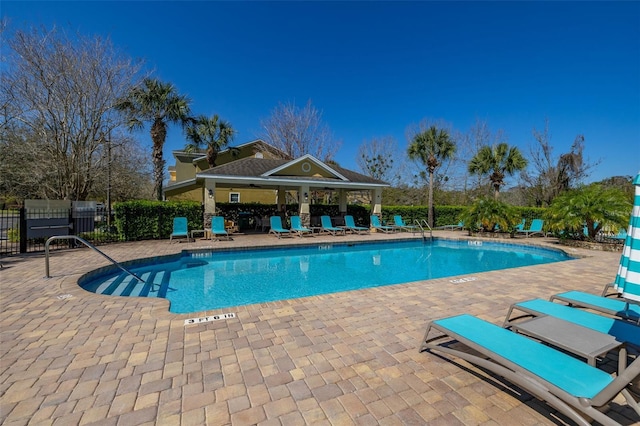 community pool with a gazebo, fence, and a patio