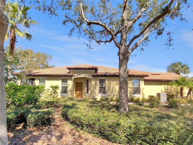 mediterranean / spanish-style home with central air condition unit, a tile roof, and stucco siding