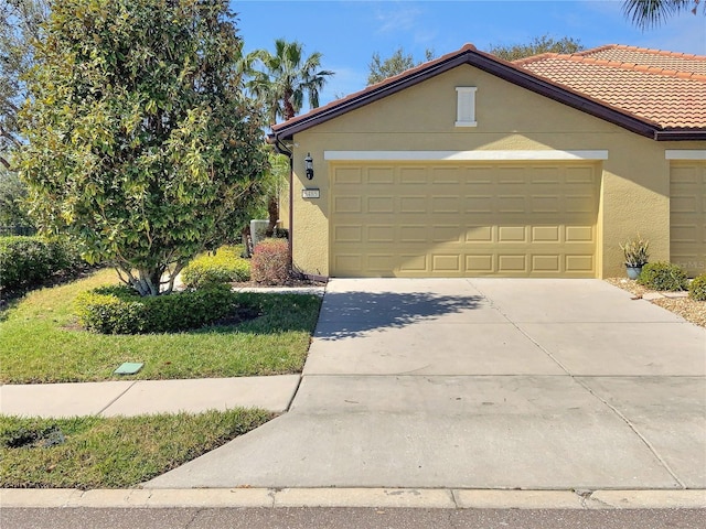 view of front of house with a garage, driveway, a tile roof, and stucco siding