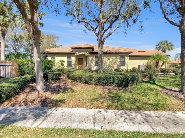 mediterranean / spanish house with a front yard, a tile roof, and stucco siding