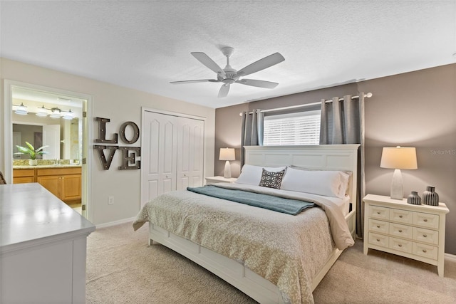 bedroom featuring light carpet, ensuite bath, a textured ceiling, and a closet