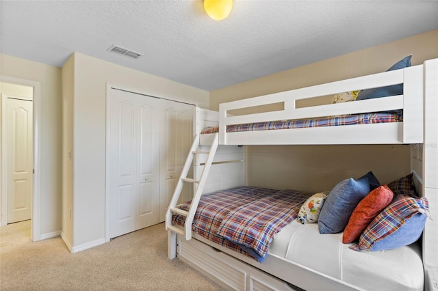 bedroom featuring baseboards, visible vents, carpet, a textured ceiling, and a closet