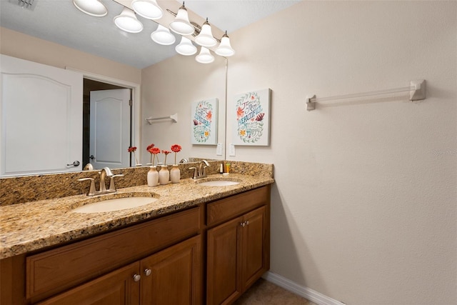 full bathroom featuring double vanity, a sink, and baseboards