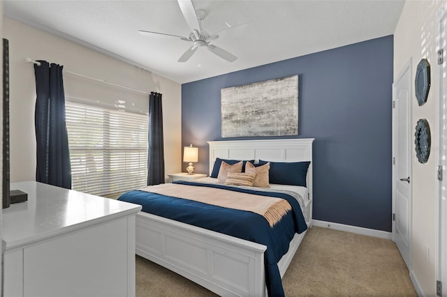 carpeted bedroom with ceiling fan and baseboards