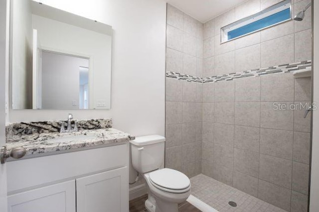 bathroom featuring tiled shower, vanity, and toilet