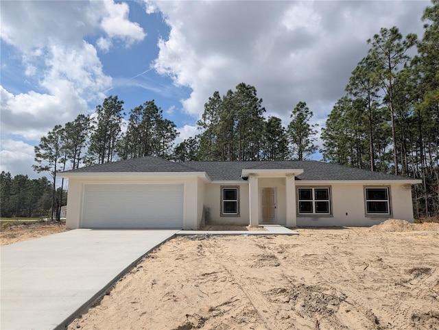 ranch-style home with concrete driveway, a shingled roof, an attached garage, and stucco siding