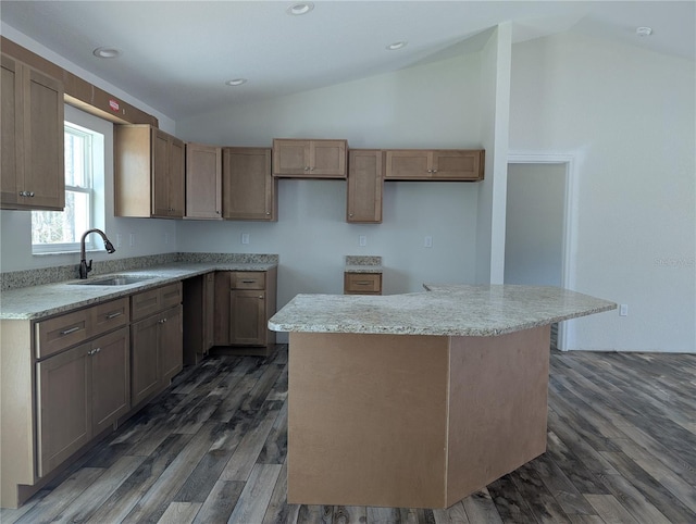 kitchen with dark wood-style flooring, lofted ceiling, recessed lighting, a kitchen island, and a sink