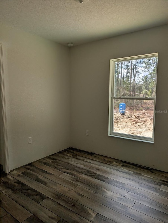 unfurnished room featuring dark wood-style flooring and a textured ceiling