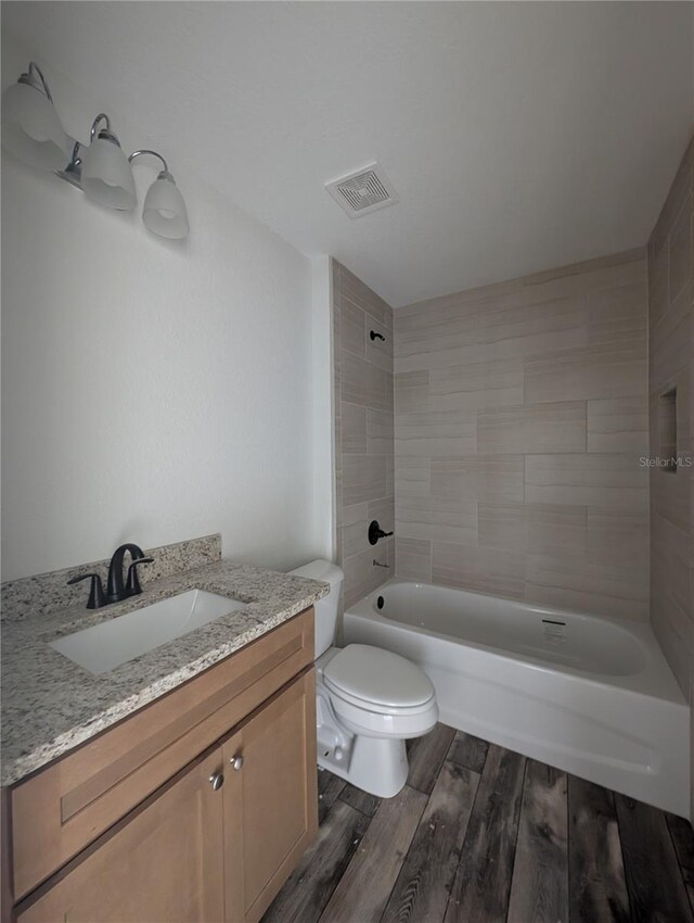 bathroom featuring visible vents, toilet, wood finished floors,  shower combination, and vanity