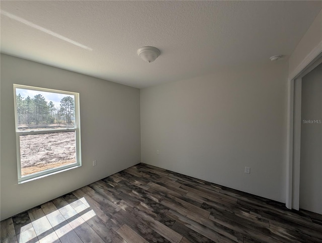 empty room featuring a textured ceiling and dark wood-style flooring