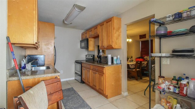 kitchen with brown cabinetry, electric range, light tile patterned flooring, a sink, and black microwave