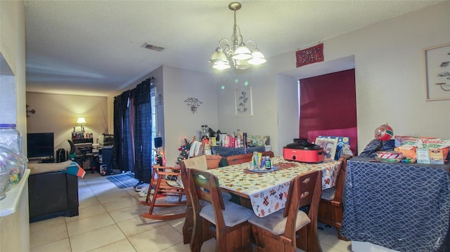 dining space featuring light tile patterned floors, a notable chandelier, a textured ceiling, and visible vents
