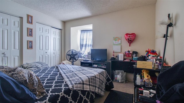 bedroom featuring two closets, carpet floors, and a textured ceiling