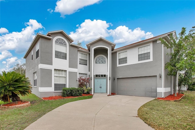 view of front of property featuring an attached garage, a front yard, concrete driveway, and stucco siding