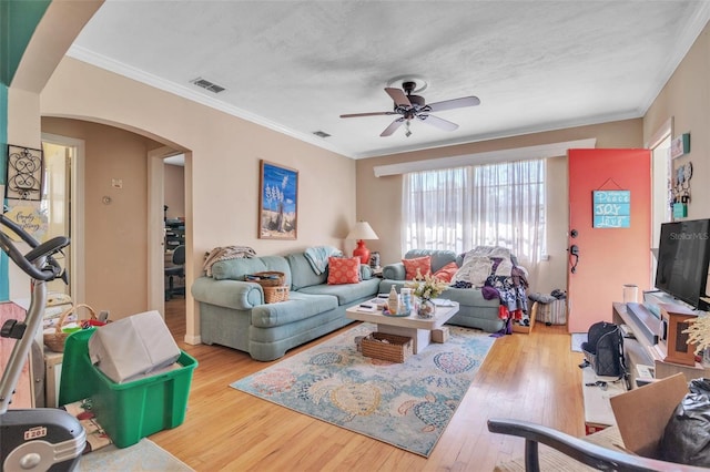 living area featuring ornamental molding, arched walkways, visible vents, and wood finished floors