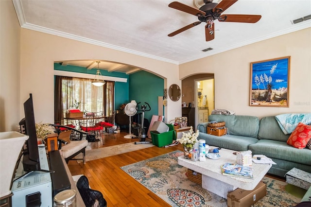 living area featuring arched walkways, hardwood / wood-style floors, visible vents, and crown molding