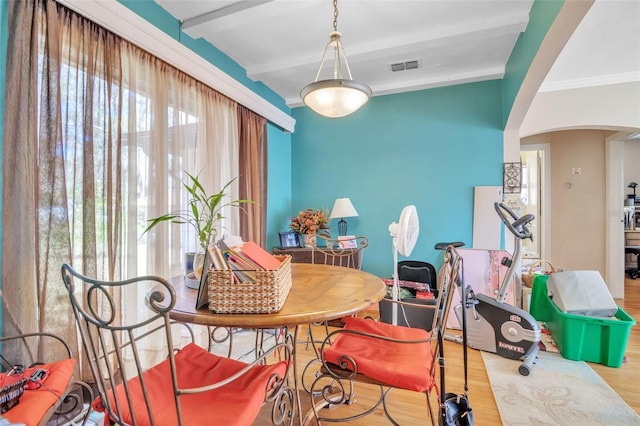 dining space with visible vents, arched walkways, wood finished floors, crown molding, and beam ceiling