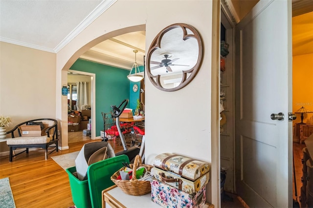 hallway with arched walkways, ornamental molding, and wood finished floors