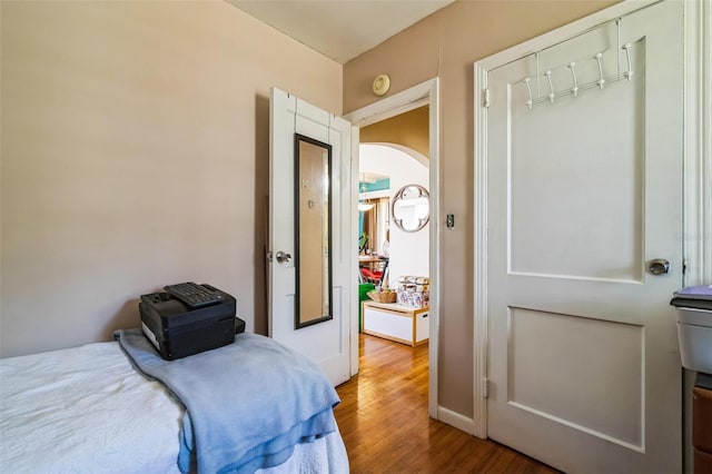 bedroom featuring arched walkways and wood finished floors