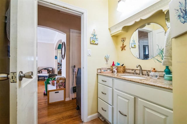 bathroom featuring baseboards, wood finished floors, vanity, and crown molding