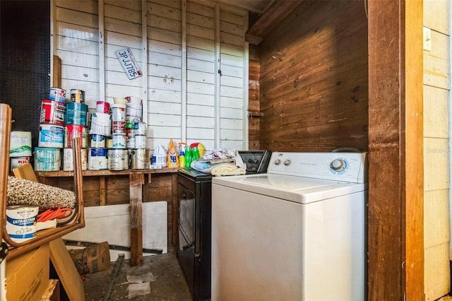 clothes washing area featuring laundry area, wooden walls, and washing machine and clothes dryer