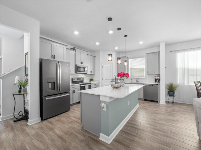 9747 Petition Way, Orlando, FL 32832 - kitchen featuring light countertops, a kitchen island, gray cabinetry, light wood-style floors, and appliances with stainless steel finishes