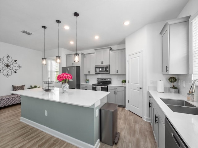 9747 Petition Way, Orlando, FL 32832 - kitchen featuring light wood-style floors, visible vents, appliances with stainless steel finishes, a sink, and gray cabinetry