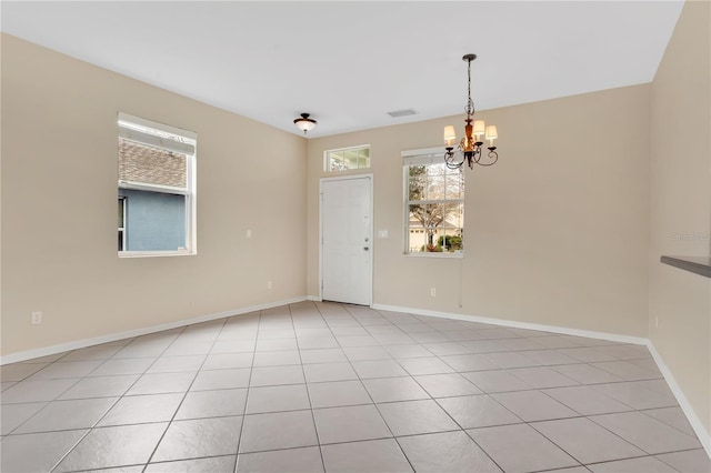 empty room featuring a chandelier, visible vents, baseboards, and light tile patterned flooring