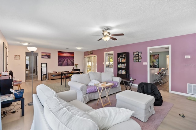1489 Magellan Cir Unit 603, Orlando, FL 32818 - living area with baseboards, a textured ceiling, visible vents, a ceiling fan, and wood finished floors