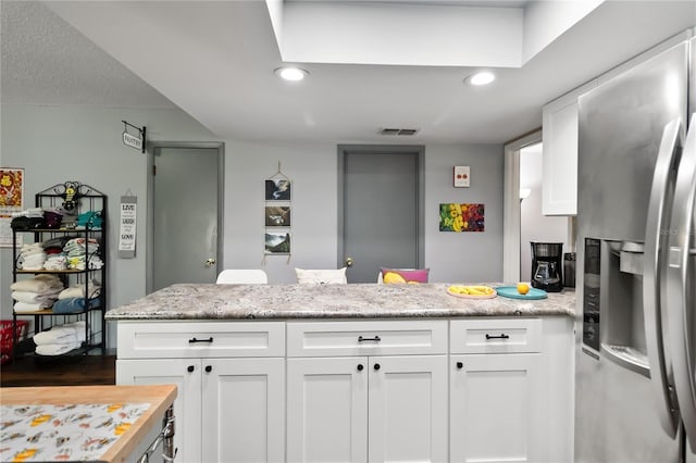1489 Magellan Cir Unit 603, Orlando, FL 32818 - kitchen with white cabinetry, visible vents, stainless steel fridge, and a peninsula