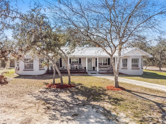 single story home featuring covered porch, a front lawn, and stucco siding