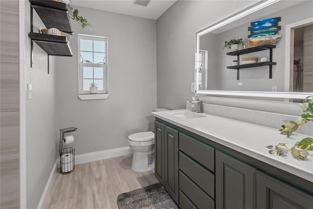 bathroom with vanity, wood finished floors, toilet, and baseboards