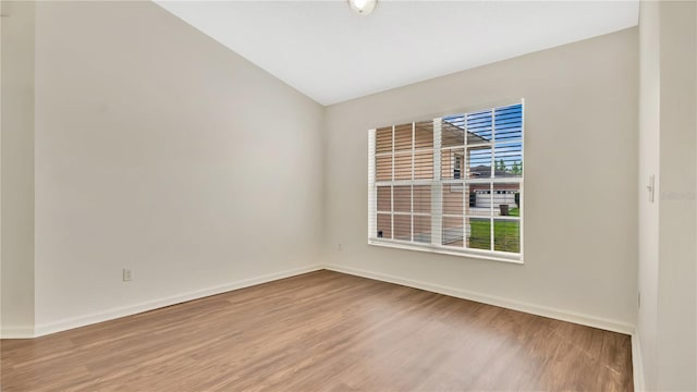 unfurnished room with vaulted ceiling, baseboards, and wood finished floors