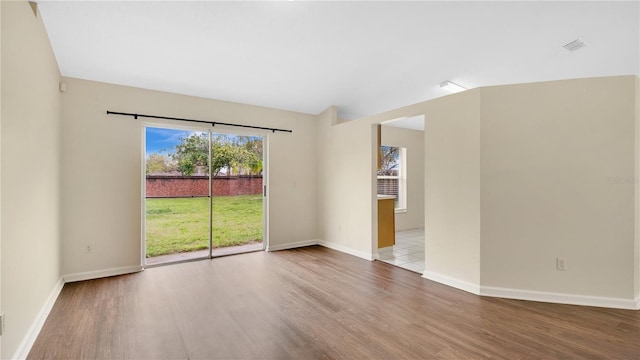 spare room featuring baseboards, visible vents, and wood finished floors