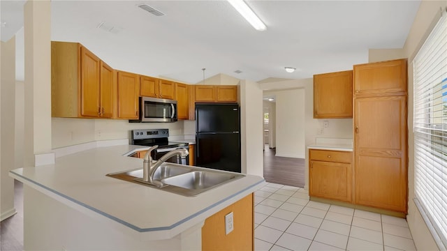 kitchen featuring stainless steel appliances, lofted ceiling, visible vents, light tile patterned flooring, and a sink