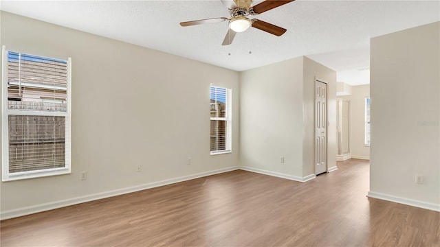 empty room with a ceiling fan, a textured ceiling, baseboards, and wood finished floors