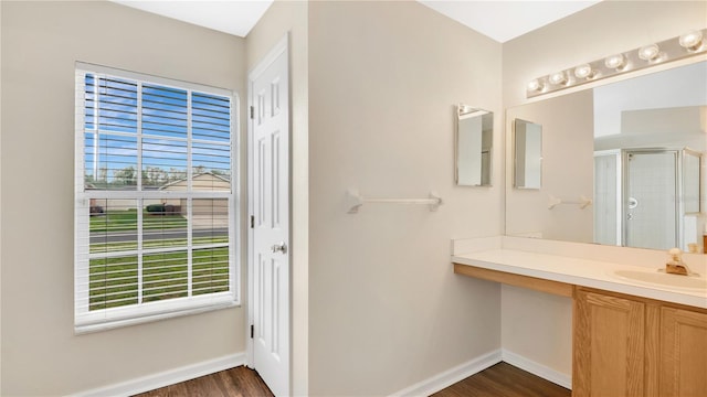 full bathroom with a stall shower, wood finished floors, vanity, and baseboards